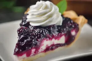 A delicious slice of wild black raspberry pie topped with fresh berries.